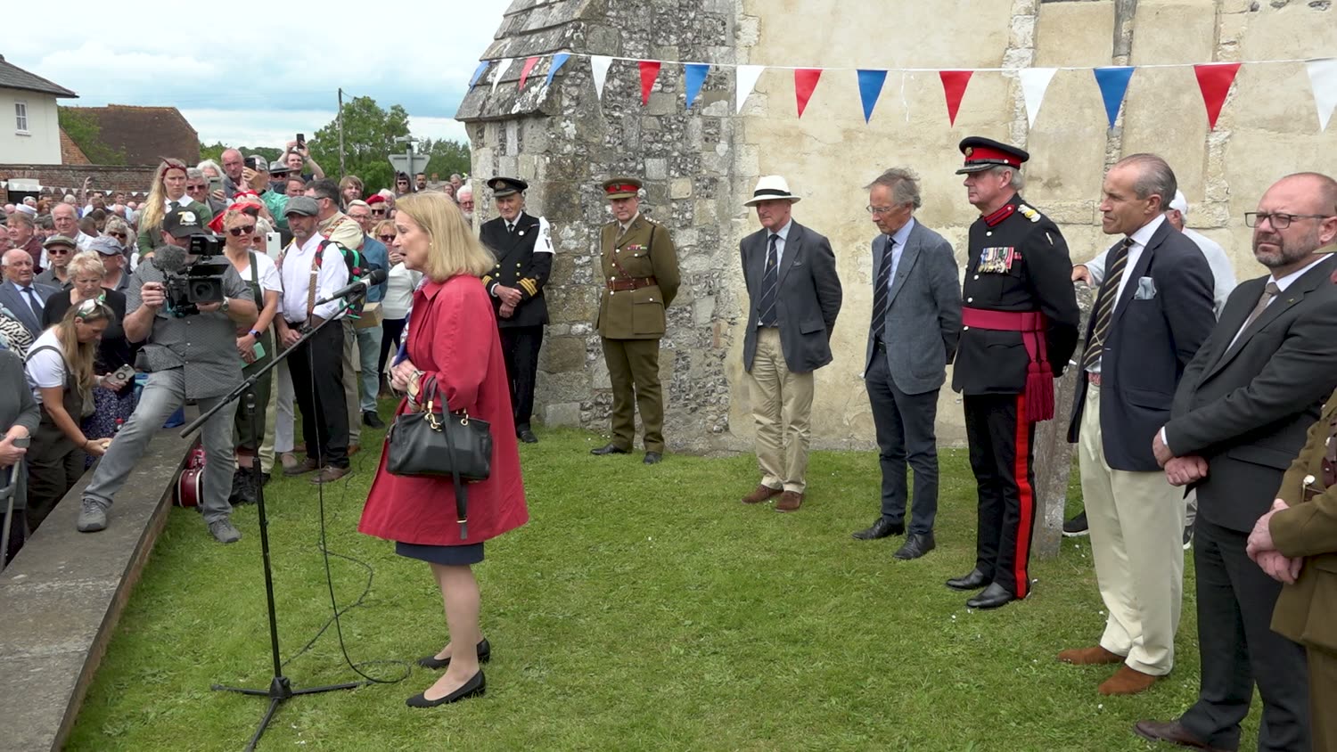 A camera filming a speech in front of a crowd at Southwick D-Day 80