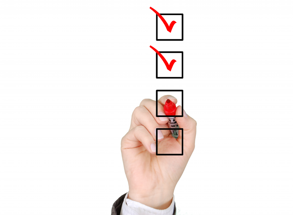 Hand holding a red marker ticking checkboxes on a checklist